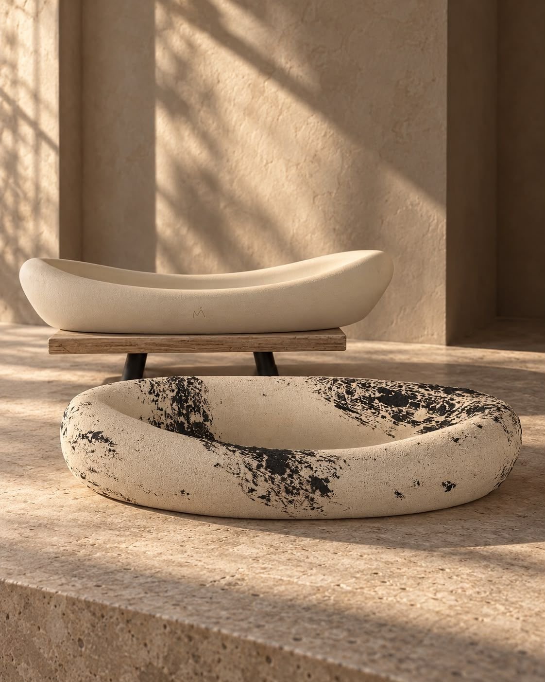 Overhead view of an ivory vessel on a stand and an ivory-and-black vessel on sand-coloured ground